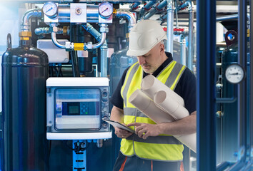 Poster - industrialist with electronic tablet. man near industrial equipment. guy works at chemical factory. 