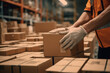 closeup on hands of a worker moving cardboard boxes in a warehouse or delivery center of an online ecommerce store, ready for shipping and delivery in a big storehouse