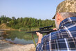 © New Africa - Man with hunting rifle near lake outdoors, back view. Space for text