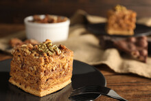 Piece of honey cake with walnuts and fork on table, closeup with space for text
