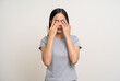 © Chanakon - Young asian beautiful woman hand rubbing eyes she's feeling depressed stress headache be tired from working standing on isolated white background she has unwell unhealthy problems.