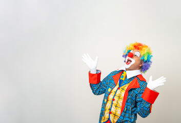 Wall Mural - Mr Clown. Portrait of Funny shocked face comedian Clown man in colorful costume wearing wig hands palm up to copy space. Happy expression amazed bozo in various pose on isolated background.