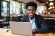 © CYBERUSS - Portrait of Cheerful Black Male Student Learning Online in Coffee Shop, Young African American Man Studies with Laptop in Cafe, Doing Homework