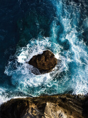 Stormy ocean waves with white foam aerial view hitting rocks in Hawaii