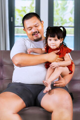 Wall Mural - Overweight Asian man at home with his little cute girl