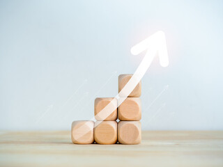 Poster - Rise up big glowing arrow on wooden cube blocks as a business chart steps isolated on white background. Business growth graph process, goal, success, and economic improvement and analysis concepts.