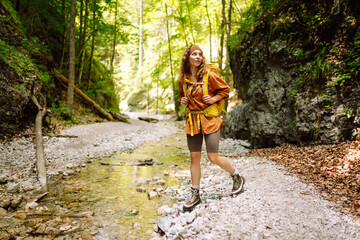 A traveler walks along a forest hiking trail in the mountains against the backdrop of mountain nature on a sunny day. Hiking, active lifestyle. Outdoor recreation concept.