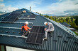 Roofers building photovoltaic solar module station on roof of house. Men electricians in helmets installing solar panel system outdoors. Concept of alternative and renewable energy. Aerial view.