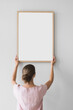 © kite_rin - Woman holding blank wooden picture frame mockup on white wall, Artwork mock-up in minimal interior design, Minimal photographer artist concept