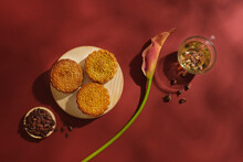 On The Red Background, Delicious Mooncakes Displayed On Wooden Tray Decorated With Watermelon Seed, Tea Cup And Flower Branch. Minimalist Concept. Traditional Chinese Mid-Autumn Festival