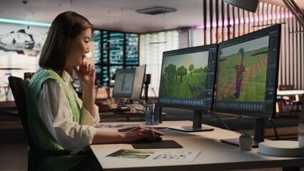 Fototapete - Female Asian Game Designer Using Desktop Computer, Designing Unique World And Characters In 3D modelling Software For RPG Video Game. Woman Working In Diverse Game Development Studio Office.