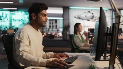 Fototapete - Indian Male Game Developer Using Desktop Computer With 3D modelling Software To Design Characters And World For Immersive Survival Video Game. Man Working In Game Design Company Diverse Office.