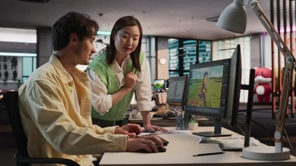 Fototapete - Caucasian Male Game Designer Using Desktop Computer With 3D modelling Software And Talking to Asian Female Project Manager in Game Development Studio Office. Diverse Colleagues Discussing New RPG Game