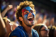 Vibrant, ecstatic young man with French flag painted on cheeks, exuding patriotism and joy amidst a blurred cheering crowd at an exciting soccer event.