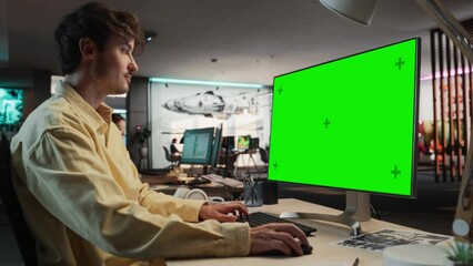 Poster - Portrait of Caucasian Man Sitting at His Desk Using Desktop Computer with Mock-up Green Screen Chromakey. Male Gameplay Animator Working in Game Design Startup, Finishing Details on a Project.