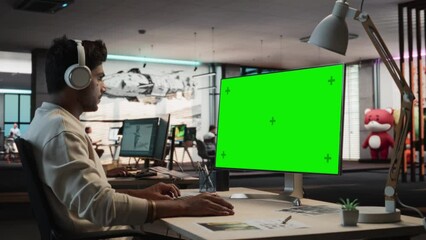Aufkleber - Portrait of Indian Man Sitting at His Desk Using Desktop Computer with Mock-up Green Screen Chromakey. Male Gameplay Animator Working in Game Design Startup Office, Finishing Details on a Project.