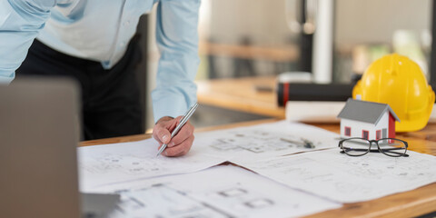 Wall Mural - Architect caucasian male working with laptop and blueprints, engineer inspection in workplace for architectural plan, sketch a construction project