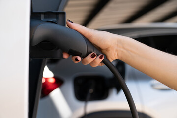 Wall Mural - Woman holding plug of electric car charging station