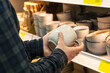 Man holding cup from a shelf in homeware store.