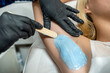 Beautician doing cosmetology procedure is removing hair in armpits with hot wax