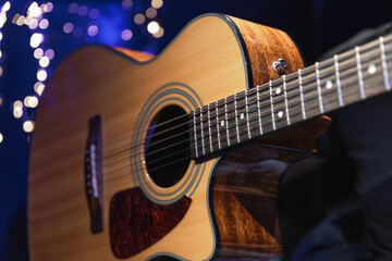 Wall Mural - Close-up, acoustic guitar on a dark background with bokeh lights.