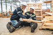 © chokniti - Warehouse worker man person has work related accident falls while trying to pick up wooden panel from the Shelf. colleagues call for help and medical assistance, injury and heal accident insurance
