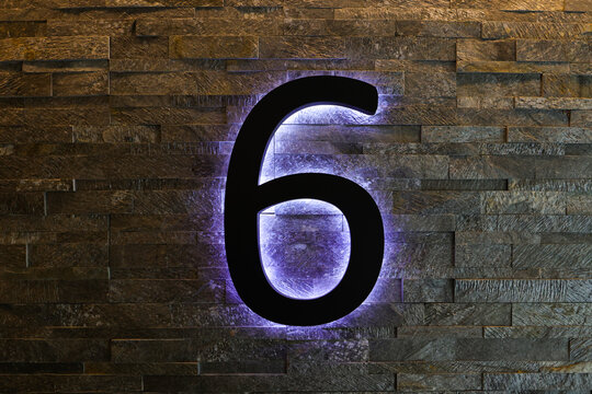 Dark  Neon Font with fluorescent purple tubes Number 6 on the dark brown brick wall.  Night Show Alphabet.