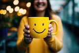 Fototapeta  - mujer sonriente aguantando entre las manos una taza amarilla con sonrisa dibujada, sobre fondo desenfocado