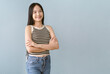 Happy smiling young Asian woman wearing casual style with sleeveless shirt with crossed arms and looking at the camera isolated isolated on plain pastel light blue background with copy space.