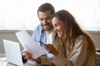 © fizkes - Happy young woman reading letter, loving couple excited by good news, taxes refund or mortgage loan approval notification, family planning budget, using laptop and online banking service