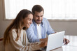 © fizkes - Happy young couple using laptop together, looking at screen, smiling woman and man reading good news in email, refund or loan mortgage approval, checking online banking service, shopping