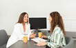 © Prostock-studio - Two Business Ladies Talking Having Meeting At Desk In Office