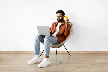 Wall Mural - Eastern Guy With Laptop And Bank Card Making Purchase Indoor