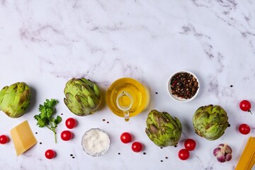 Wall Mural - Culinary background with artichokes, seasonings, cheese, garlic and olive oil on a light background with space for text.