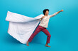 Full body photo of attractive young man blanket cape super hero flying wear trendy white pajama clothes isolated on blue color background