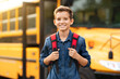 © Prostock-studio - Happy smiling preteen boy standing near yellow school bus outdoors