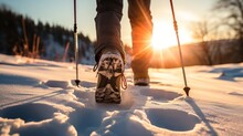 Shoes of a hiker in the snow with hiking sticks, forest, winter, sunset