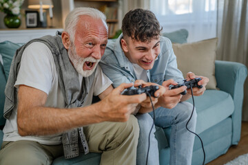 Wall Mural - teenager male and his grandfather senior man play console video game