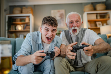 Wall Mural - teenager male and his grandfather senior man play console video game