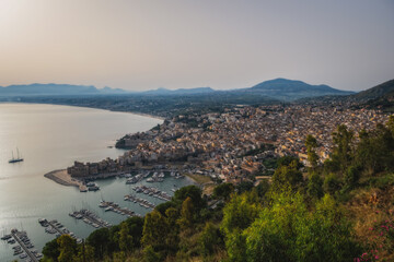 Wall Mural - Panoramic view of Castellammare del Golfo from the coastal path of the Zingaro Natural Park, Sicily, Italy. Top view, sunrise time. June 2023