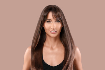 Wall Mural - Hair styling. Portrait of beautiful woman with straight long hair on pale brown background