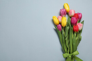 Wall Mural - Beautiful colorful tulip flowers and ribbon on light grey background, flat lay. Space for text