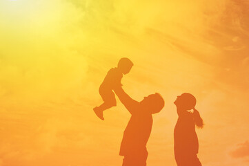 Wall Mural - Happy parents and child playing outdoors in the sunset. Loving family lifestyle concept. 