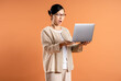 Portrait of  middle age Asian woman using laptop on brown background.