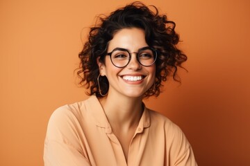 Wall Mural - Portrait of a smiling young woman in eyeglasses on orange background