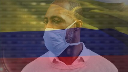 Poster - Animation of waving colombia flag over portrait of african american man wearing face mask on street