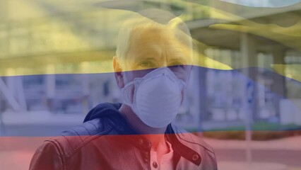 Poster - Animation of waving colombia flag over portrait of caucasian man wearing face mask on the street