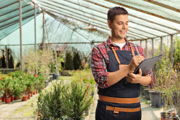 Wall Mural - Male florist holding a clipboard and standing in a greenhouse