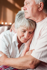 Worried senior woman embracing upset old man