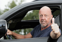 Mature Man Driving Car Shows Thumb Up